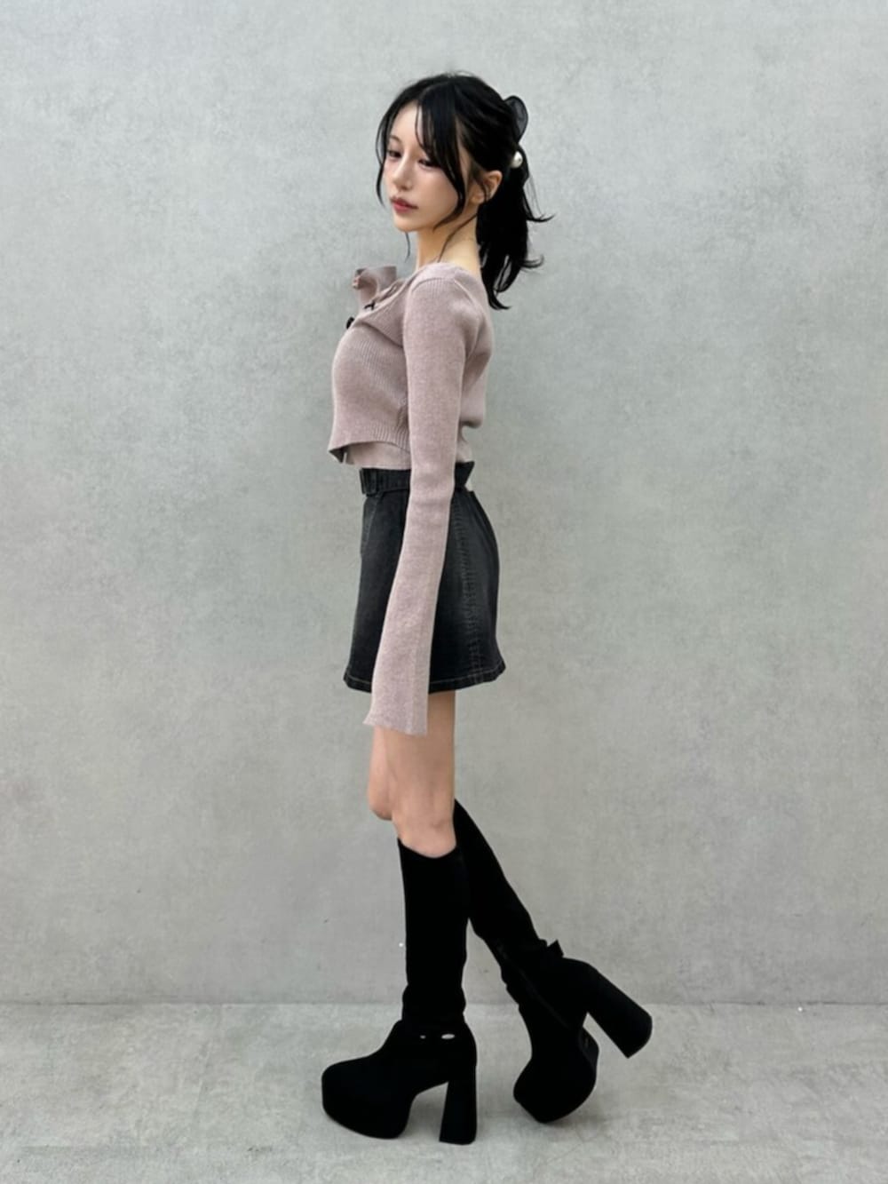 ブラック系のデニムスカート、ブラック系のブーツ、ベージュ系のニット/セーターを着用したレディースの秋コーディネートの4枚目の写真