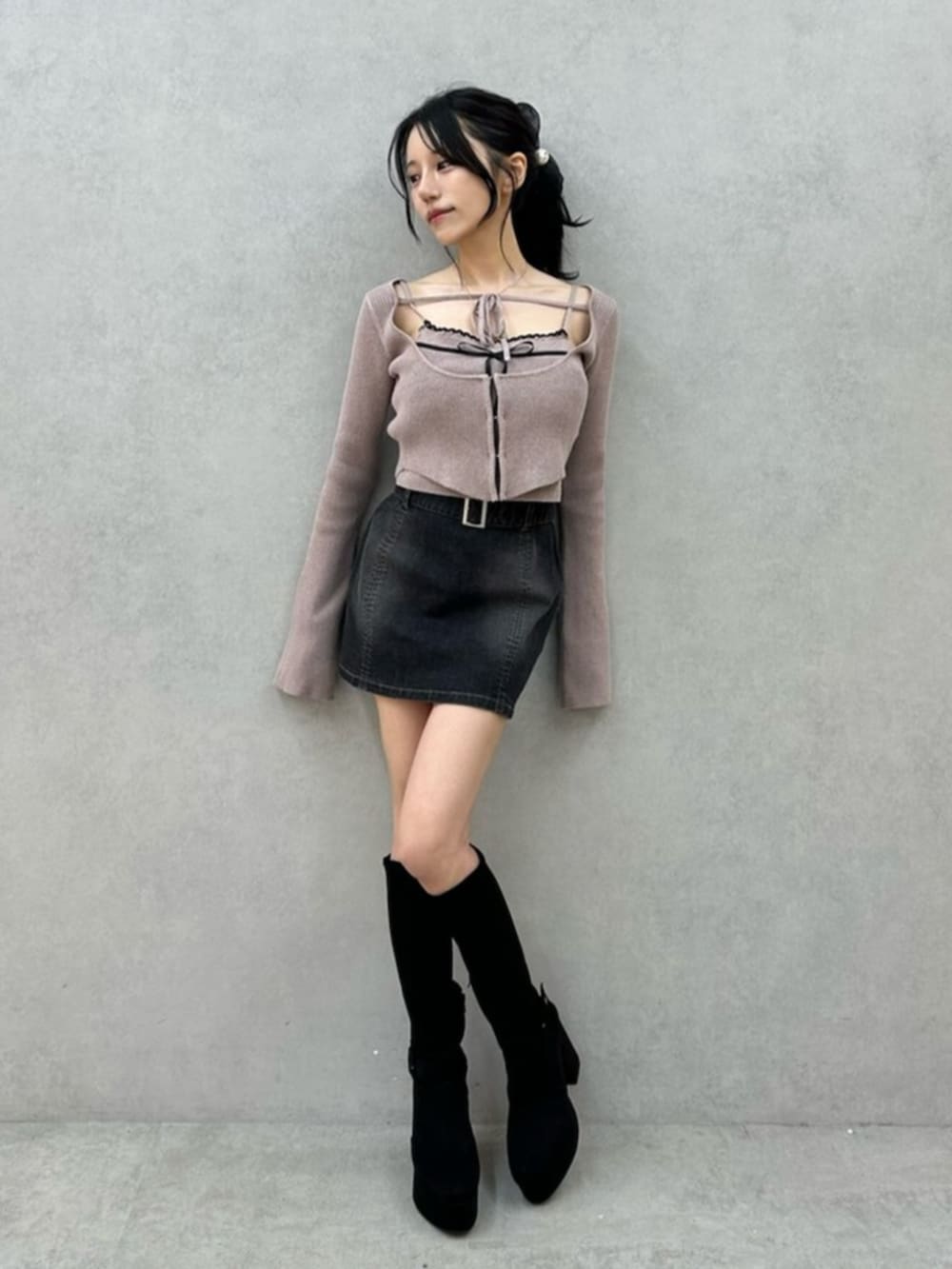 ブラック系のデニムスカート、ブラック系のブーツ、ベージュ系のニット/セーターを着用したレディースの秋コーディネートの2枚目の写真