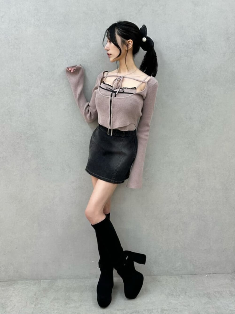 ブラック系のデニムスカート、ブラック系のブーツ、ベージュ系のニット/セーターを着用したレディースの秋コーディネートの5枚目の写真