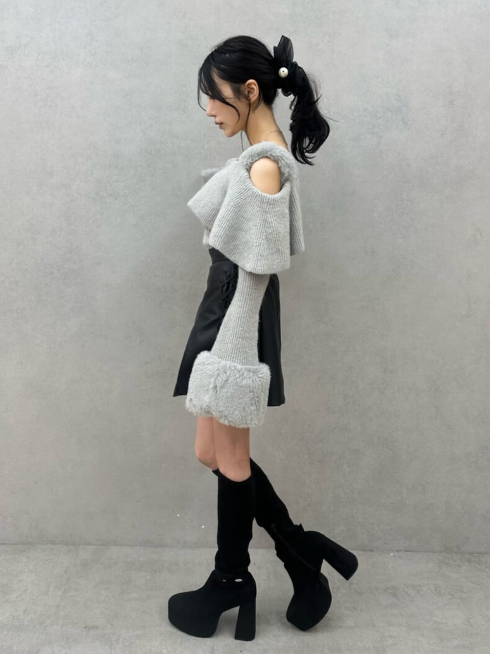 グレー系のニット/セーター、ブラック系のスカート、ブラック系のブーツを着用したレディースの秋コーディネートの4枚目の写真