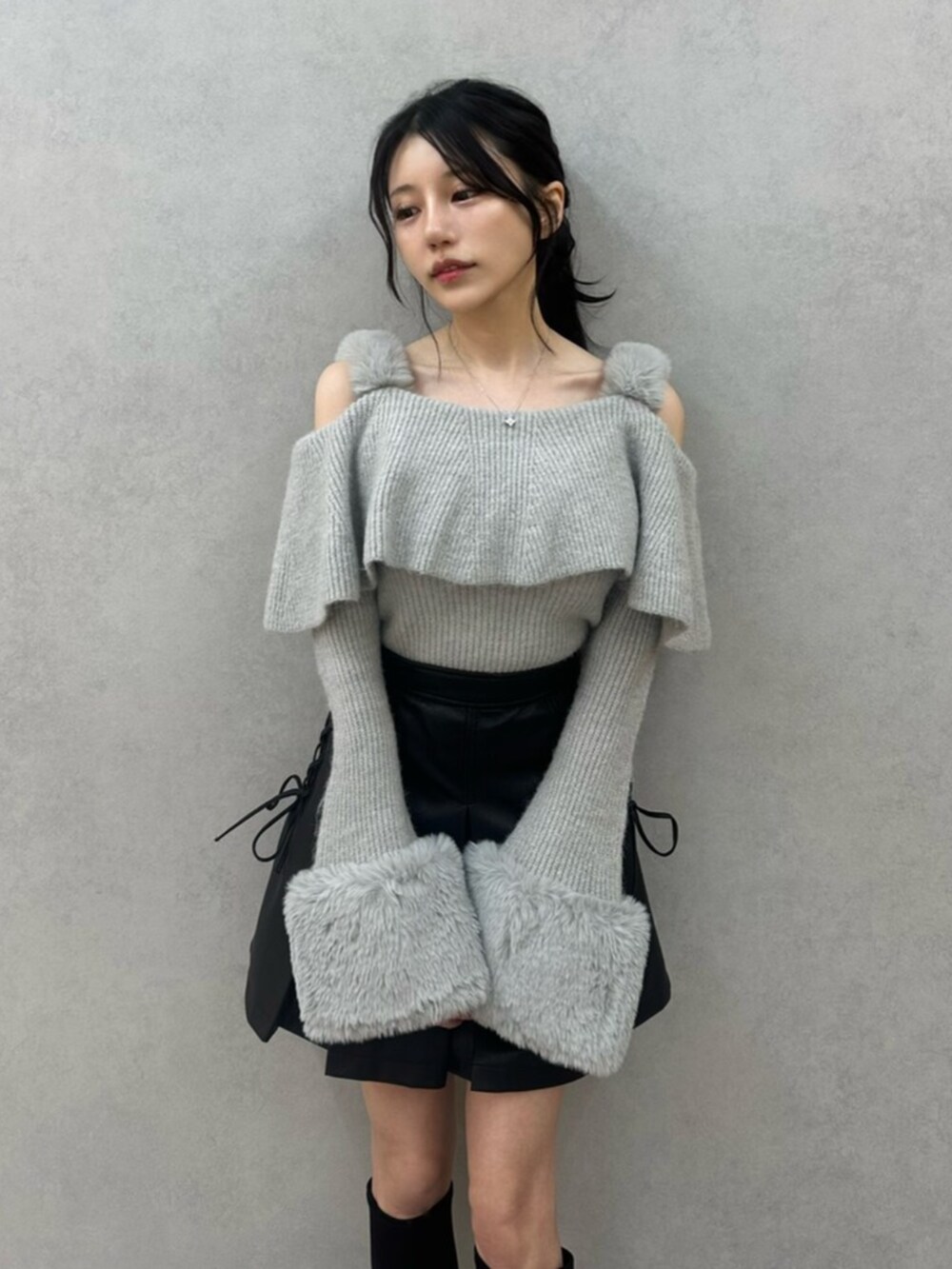 グレー系のニット/セーター、ブラック系のスカート、ブラック系のブーツを着用したレディースの秋コーディネートの5枚目の写真