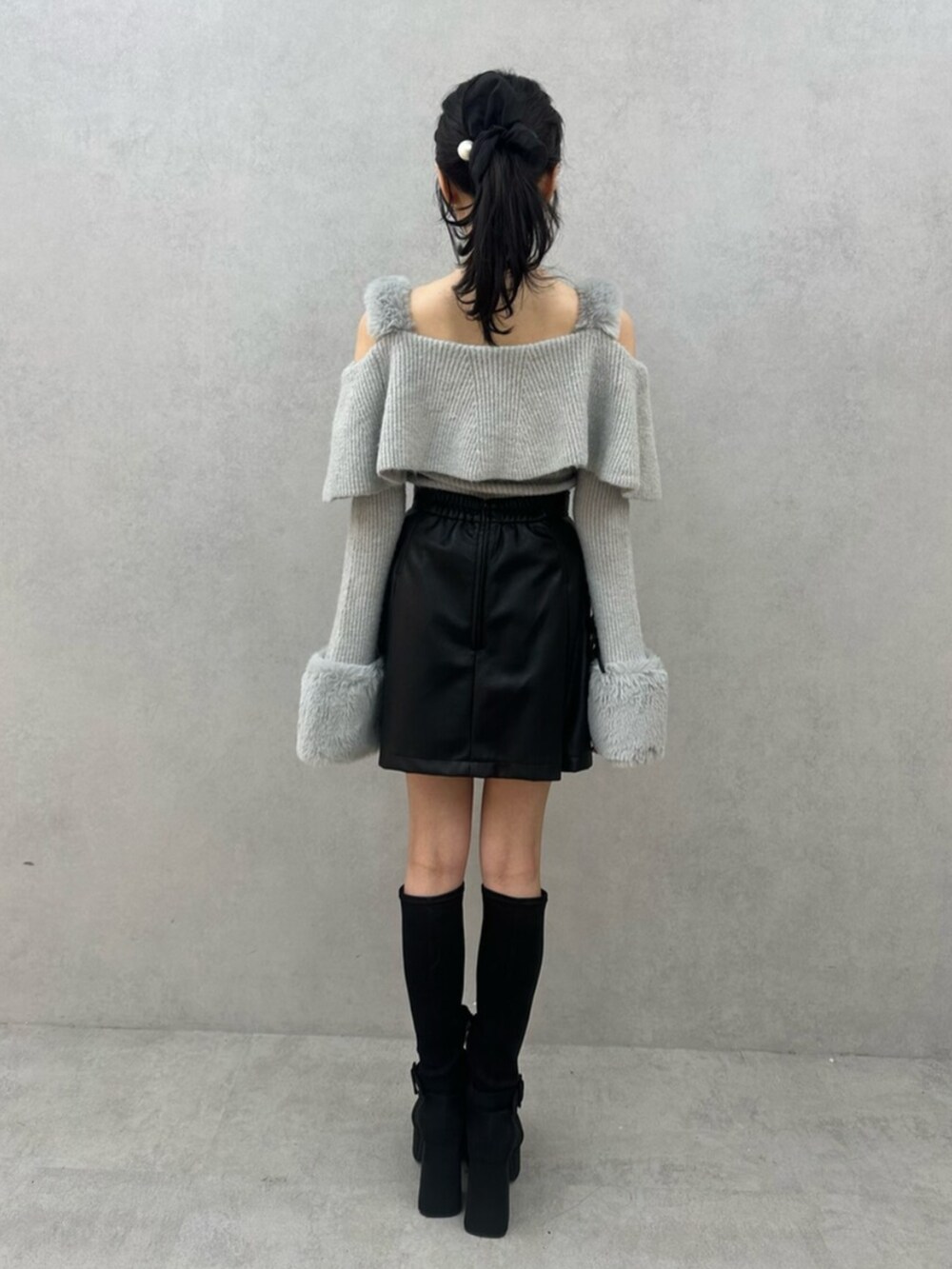 グレー系のニット/セーター、ブラック系のスカート、ブラック系のブーツを着用したレディースの秋コーディネートの6枚目の写真