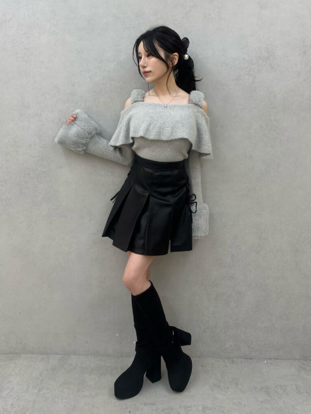 グレー系のニット/セーター、ブラック系のスカート、ブラック系のブーツを着用したレディースの秋コーディネートの2枚目の写真