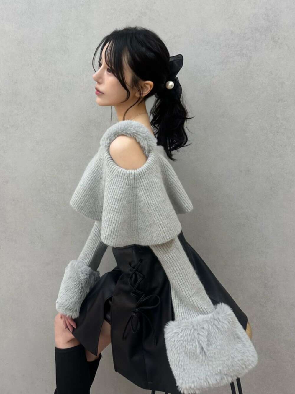 グレー系のニット/セーター、ブラック系のスカート、ブラック系のブーツを着用したレディースの秋コーディネートの8枚目の写真