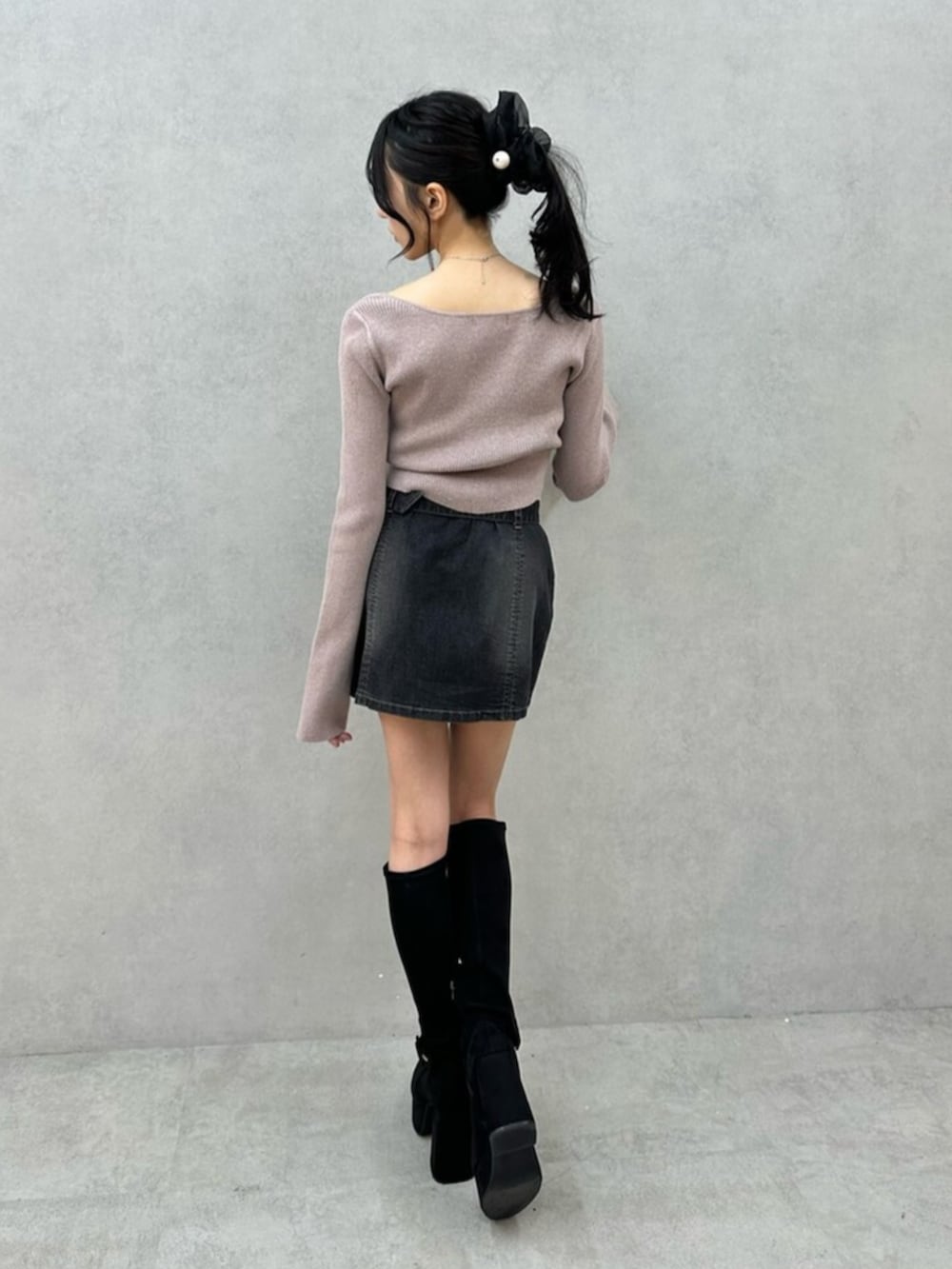 ブラック系のデニムスカート、ブラック系のブーツ、ベージュ系のニット/セーターを着用したレディースの秋コーディネートの6枚目の写真