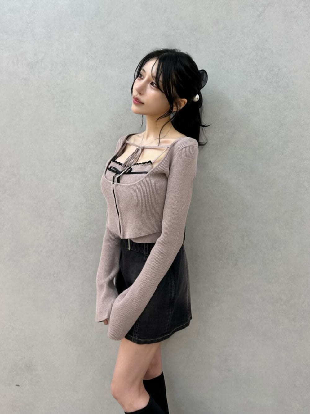 ブラック系のデニムスカート、ブラック系のブーツ、ベージュ系のニット/セーターを着用したレディースの秋コーディネートの7枚目の写真