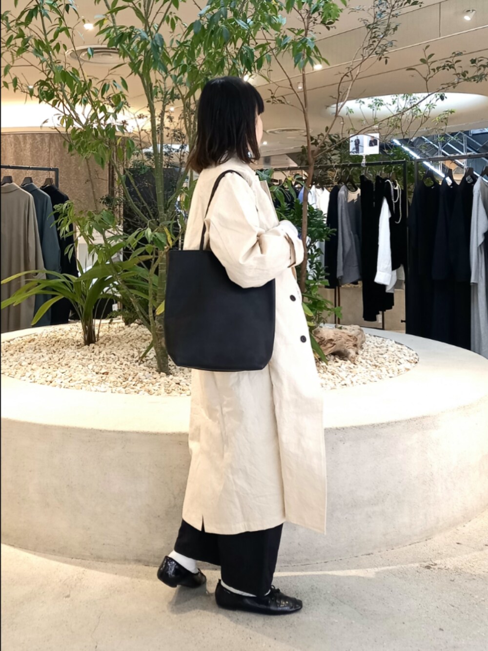 ベージュ系のスウェット、ホワイト系のステンカラーコート、ブラック系のTシャツ/カットソーを着用したレディースの冬コーディネートの3枚目の写真