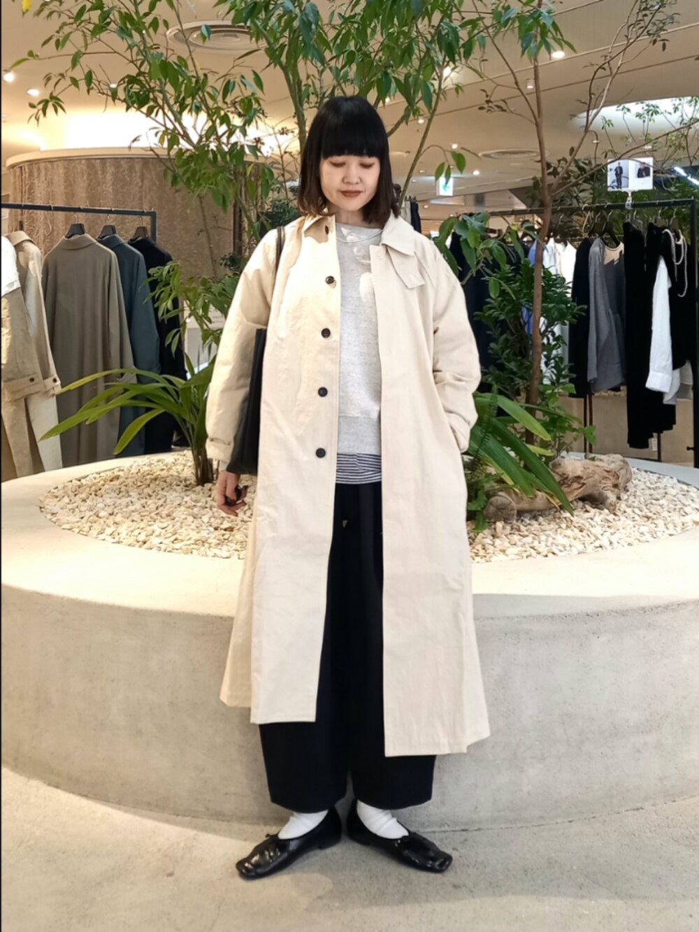 ベージュ系のスウェット、ホワイト系のステンカラーコート、ブラック系のTシャツ/カットソーを着用したレディースの冬コーディネートの2枚目の写真