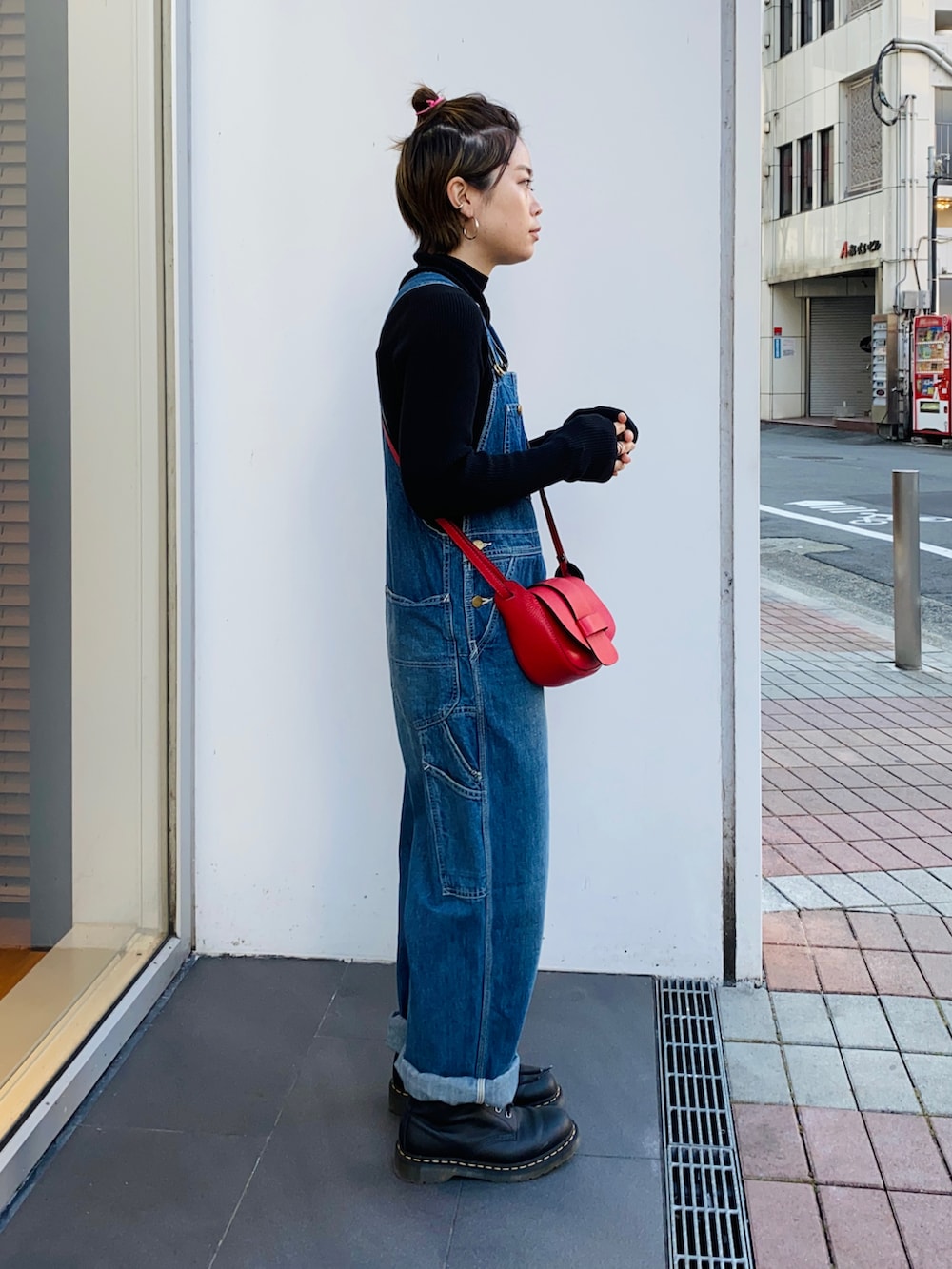 ブラック系のニット/セーター、ブルー系のサロペット/オーバーオール、レッド系のショルダーバッグを着用したレディースの冬コーディネートの3枚目の写真