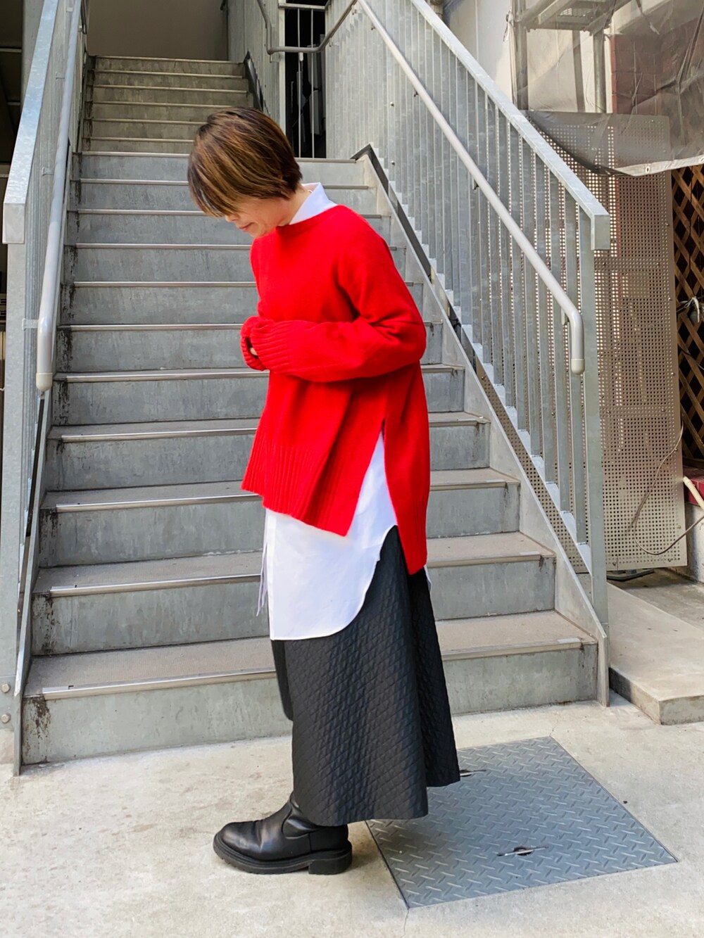 レッド系のニット/セーター、ホワイト系のシャツ/ブラウス、ブラック系のスカートを着用したレディースの冬コーディネートの2枚目の写真