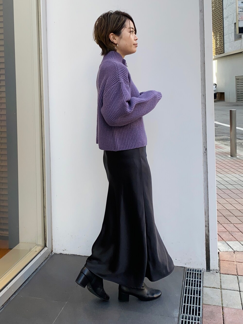 パープル系のニット/セーター、ブラック系のスカート、ブラック系のブーツを着用したレディースの冬コーディネートの2枚目の写真