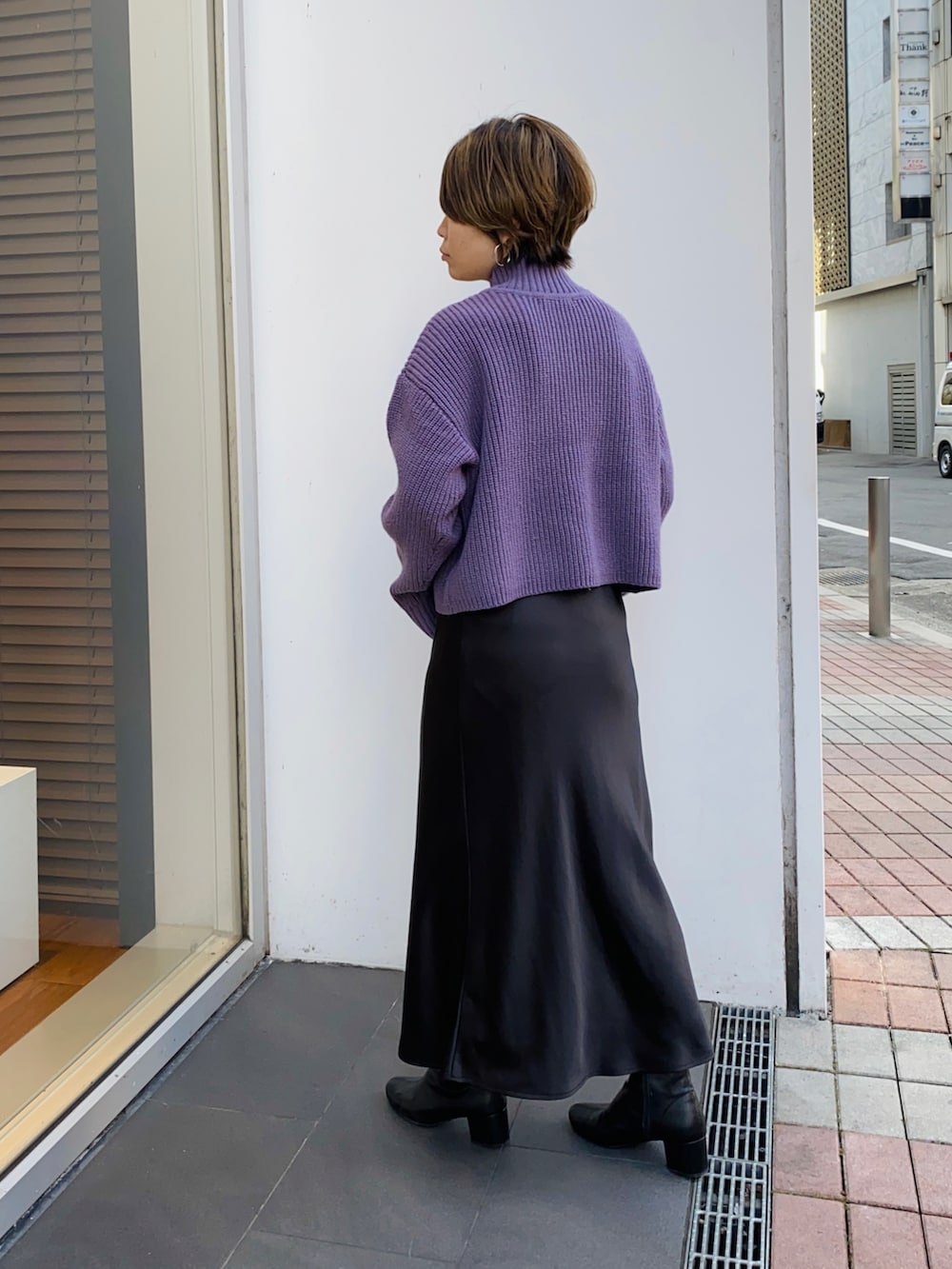 パープル系のニット/セーター、ブラック系のスカート、ブラック系のブーツを着用したレディースの冬コーディネートの3枚目の写真