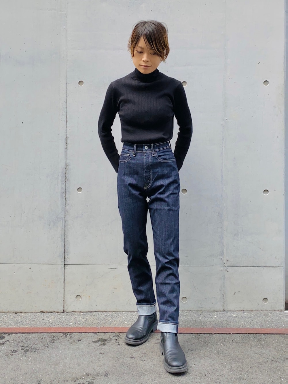 ブラック系のニット/セーター、ブルー系のデニムパンツ、ベージュ系のトレンチコートを着用したレディースの秋コーディネートの2枚目の写真