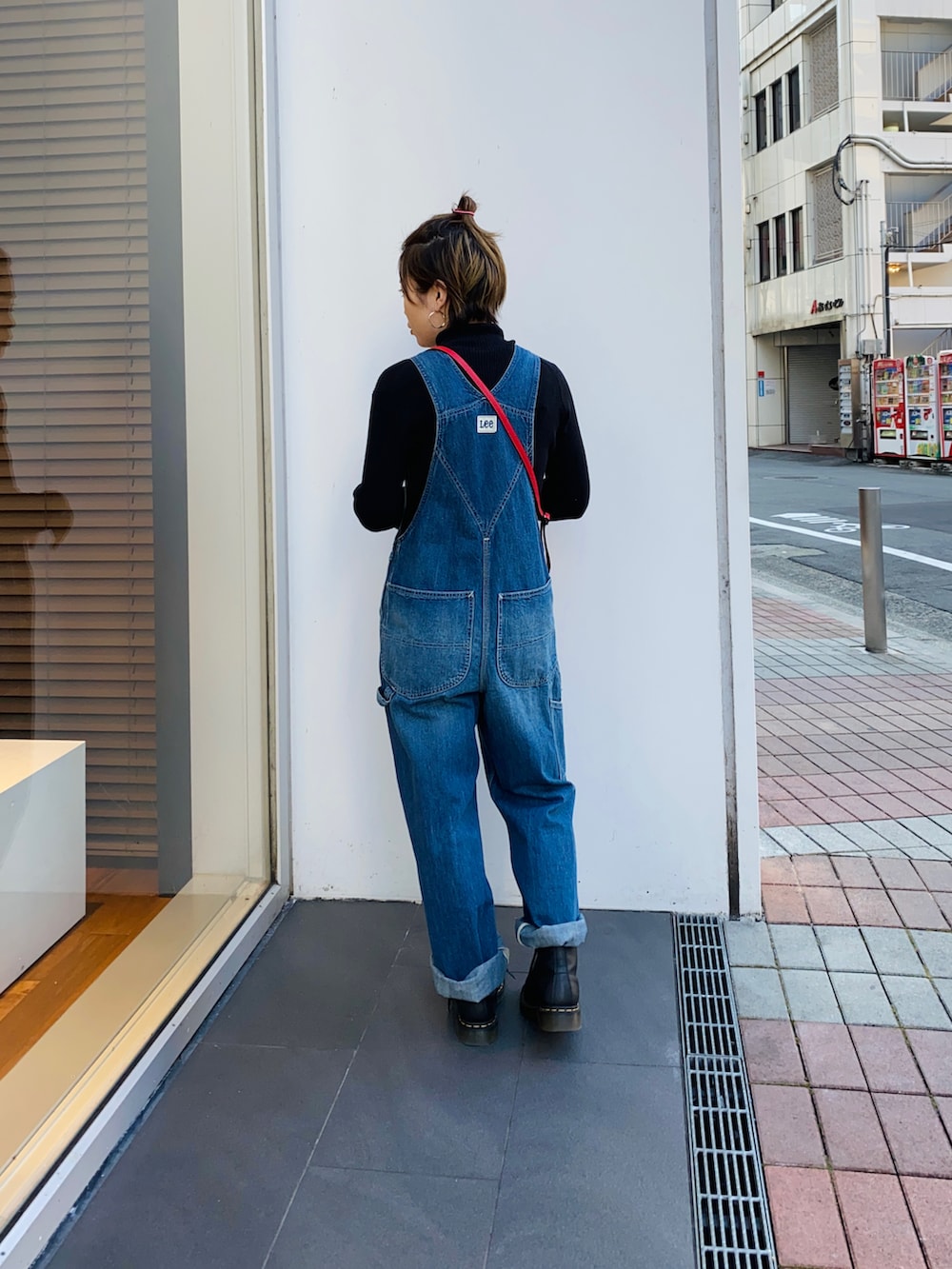 ブラック系のニット/セーター、ブルー系のサロペット/オーバーオール、レッド系のショルダーバッグを着用したレディースの冬コーディネートの2枚目の写真