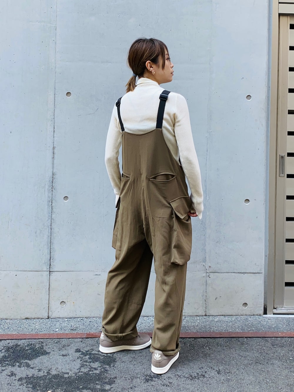 ブラック系のニット/セーター、グリーン系のサロペット/オーバーオール、ブラック系のデニムジャケットを着用したレディースの秋コーディネートの5枚目の写真