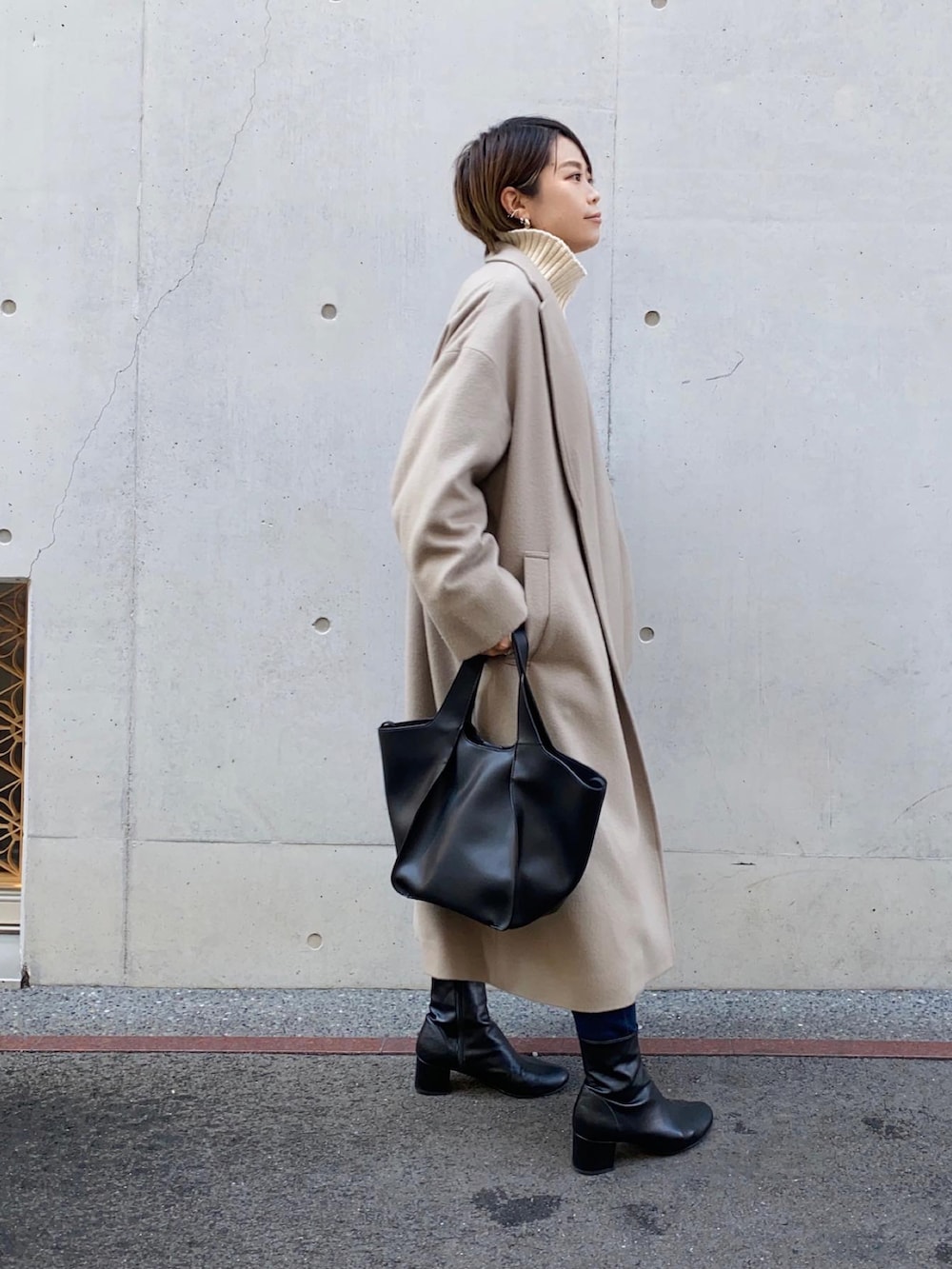 ホワイト系のチェスターコート、ブルー系のニット/セーター、ブラック系のブーツを着用したレディースの秋コーディネートの2枚目の写真