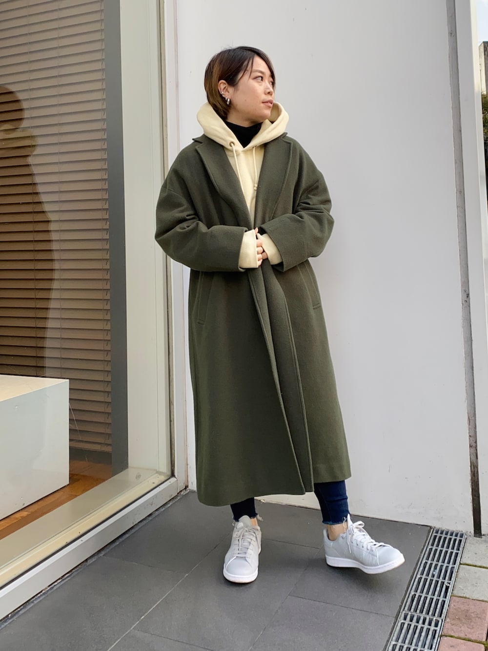 グリーン系のチェスターコート、グレー系のパーカーを着用したレディースの秋コーディネートの2枚目の写真