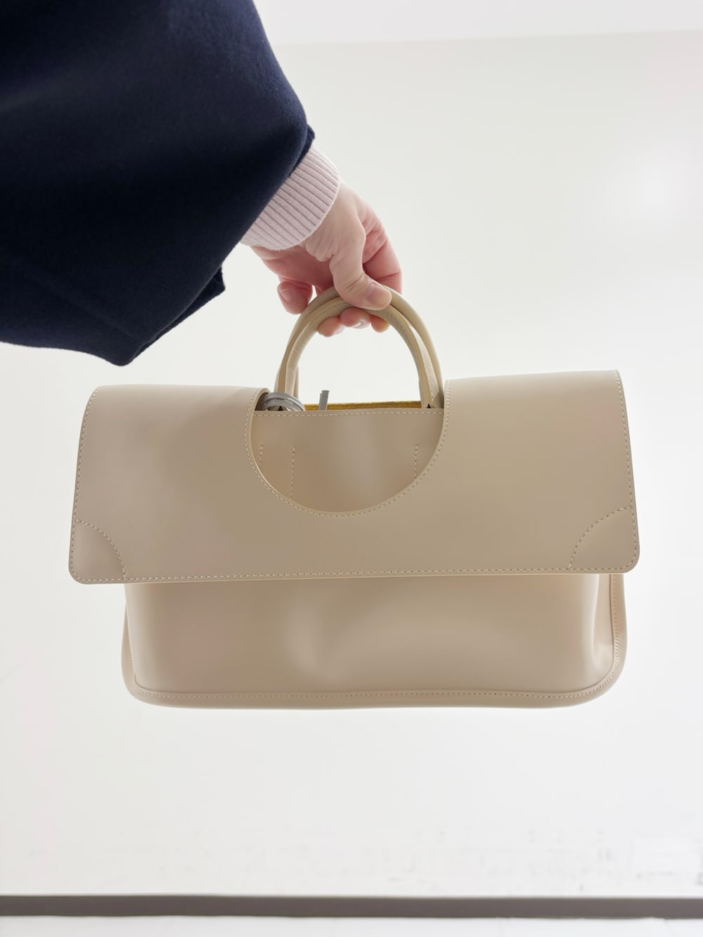 イエロー系のハンドバッグ、ピンク系のニット/セーター、ブルー系のテーラードジャケットを着用したレディースの冬コーディネートの10枚目の写真