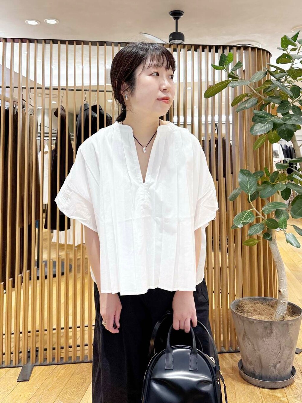 ブラック系のショルダーバッグ、ブラック系のその他パンツ、ホワイト系のシャツ/ブラウスを着用したレディースの夏コーディネートの5枚目の写真