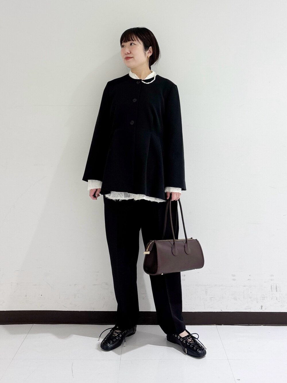 ブラック系のノーカラージャケット、ホワイト系のシャツ/ブラウス、ブラウン系のショルダーバッグを着用したレディースの冬コーディネートの5枚目の写真