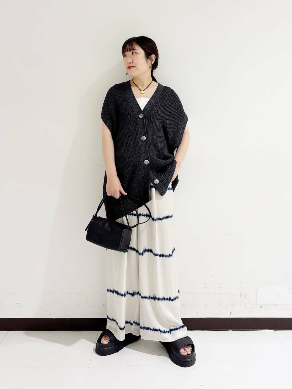 ホワイト系のタンクトップ、ホワイト系のその他パンツ、ブラック系のショルダーバッグを着用したレディースの夏コーディネートの5枚目の写真