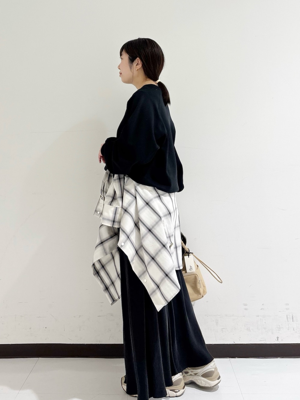 ブラック系のスウェット、ホワイト系のシャツ/ブラウス、ベージュ系のショルダーバッグを着用したレディースの冬コーディネートの2枚目の写真