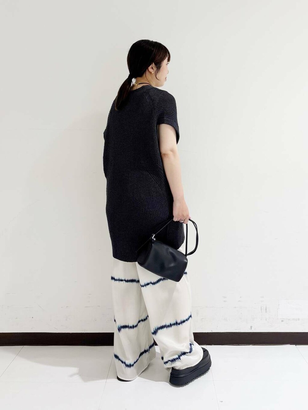 ホワイト系のタンクトップ、ホワイト系のその他パンツ、ブラック系のショルダーバッグを着用したレディースの夏コーディネートの3枚目の写真