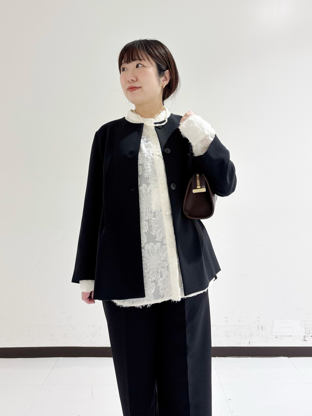 ブラック系のノーカラージャケット、ホワイト系のシャツ/ブラウス、ブラウン系のショルダーバッグを着用したレディースの冬コーディネートの7枚目の写真