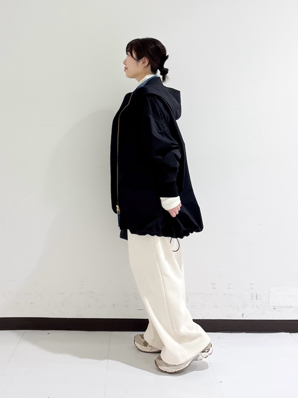 ホワイト系のニット/セーター、ブルー系のシャツ/ブラウス、ブラック系のマウンテンパーカーを着用したレディースの秋コーディネートの2枚目の写真