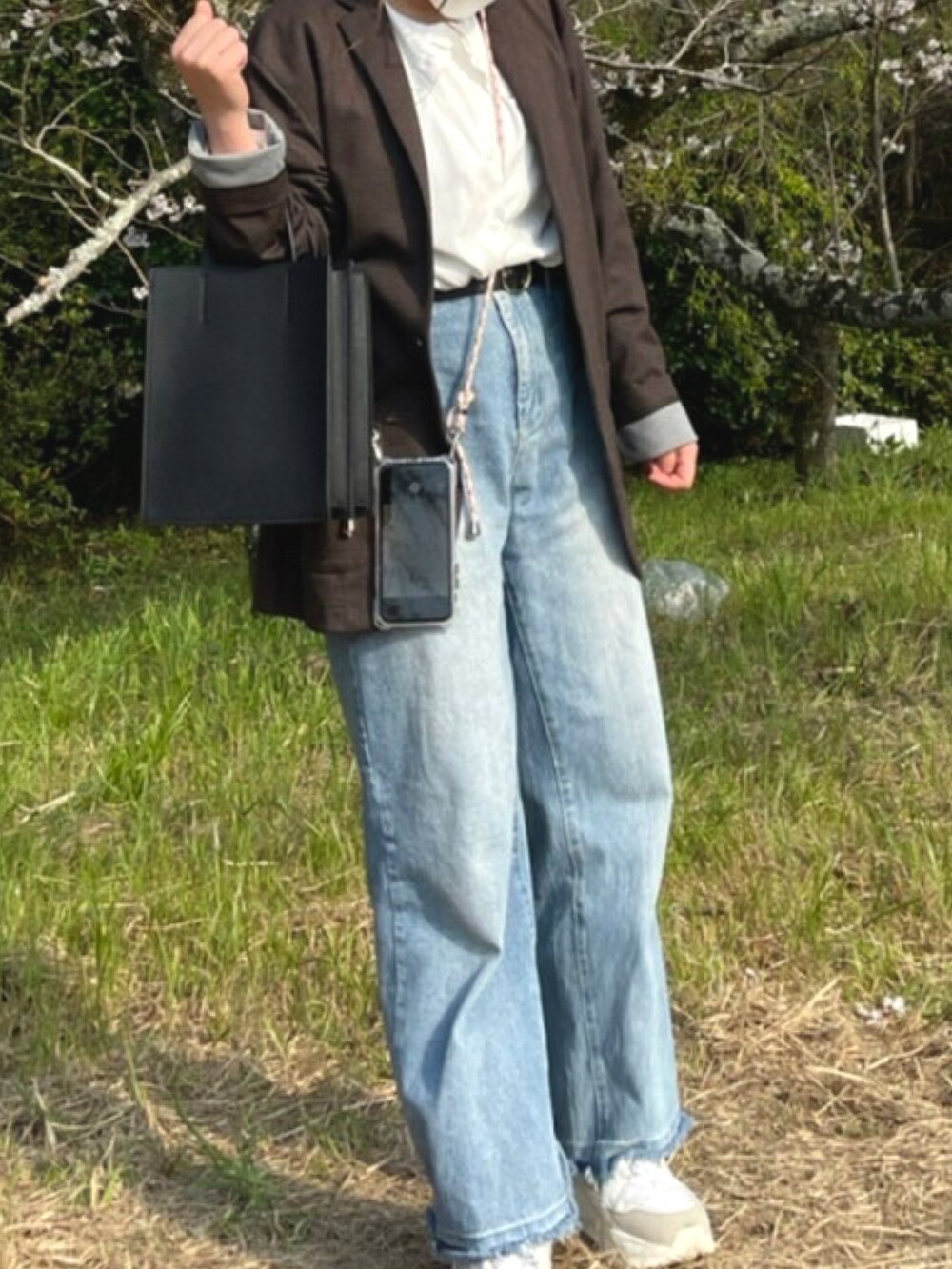 ブラック系のバッグ、ホワイト系のシャツ/ブラウス、ブルー系のデニムパンツを着用したレディースの春コーディネートの2枚目の写真