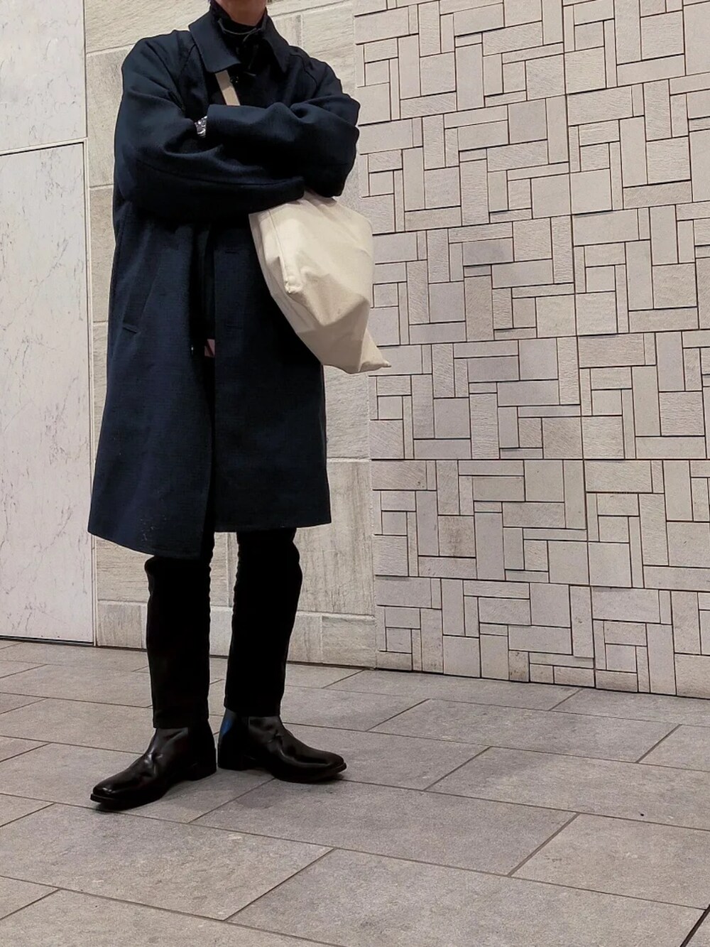 ブルー系のチェスターコート、ブラック系のパンツ、ピンク系のスウェットを着用したメンズの冬コーディネートの2枚目の写真