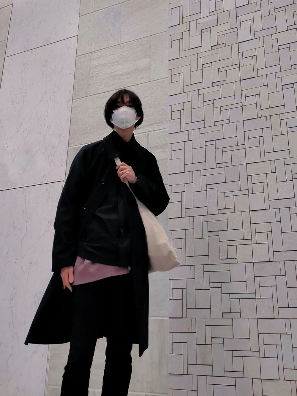 ブルー系のチェスターコート、ブラック系のパンツ、ピンク系のスウェットを着用したメンズの冬コーディネートの5枚目の写真