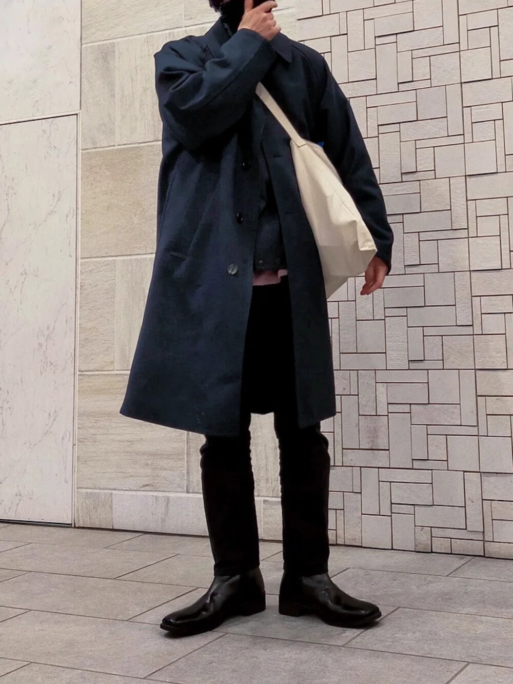 ブルー系のチェスターコート、ブラック系のパンツ、ピンク系のスウェットを着用したメンズの冬コーディネートの3枚目の写真