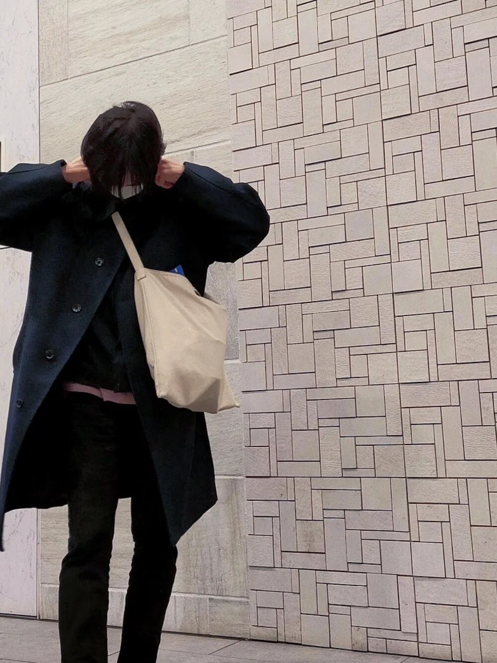 ブルー系のチェスターコート、ブラック系のパンツ、ピンク系のスウェットを着用したメンズの冬コーディネートの4枚目の写真