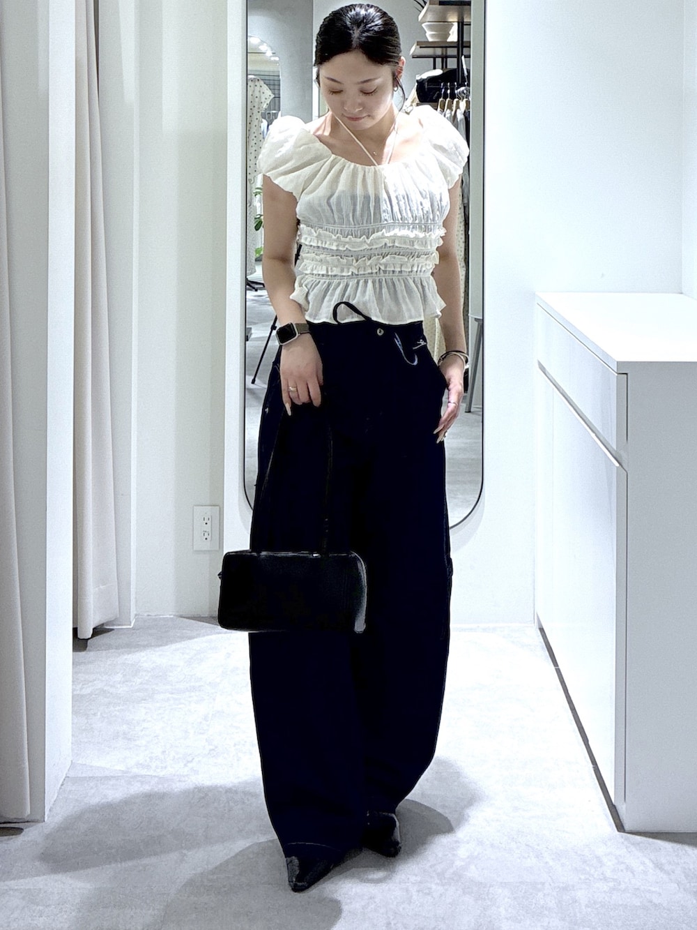 ブルー系のデニムパンツ、ホワイト系のシャツ/ブラウス、ブラック系のショルダーバッグを着用したレディースの夏コーディネートの3枚目の写真