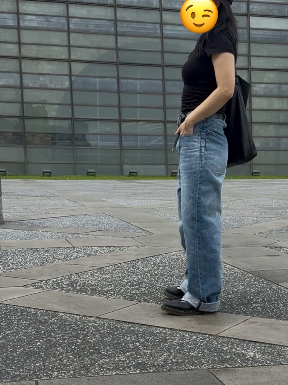 ブラック系のTシャツ/カットソー、ブラック系のドラムバッグ、ブルー系のデニムパンツを着用したレディースの秋コーディネートの2枚目の写真