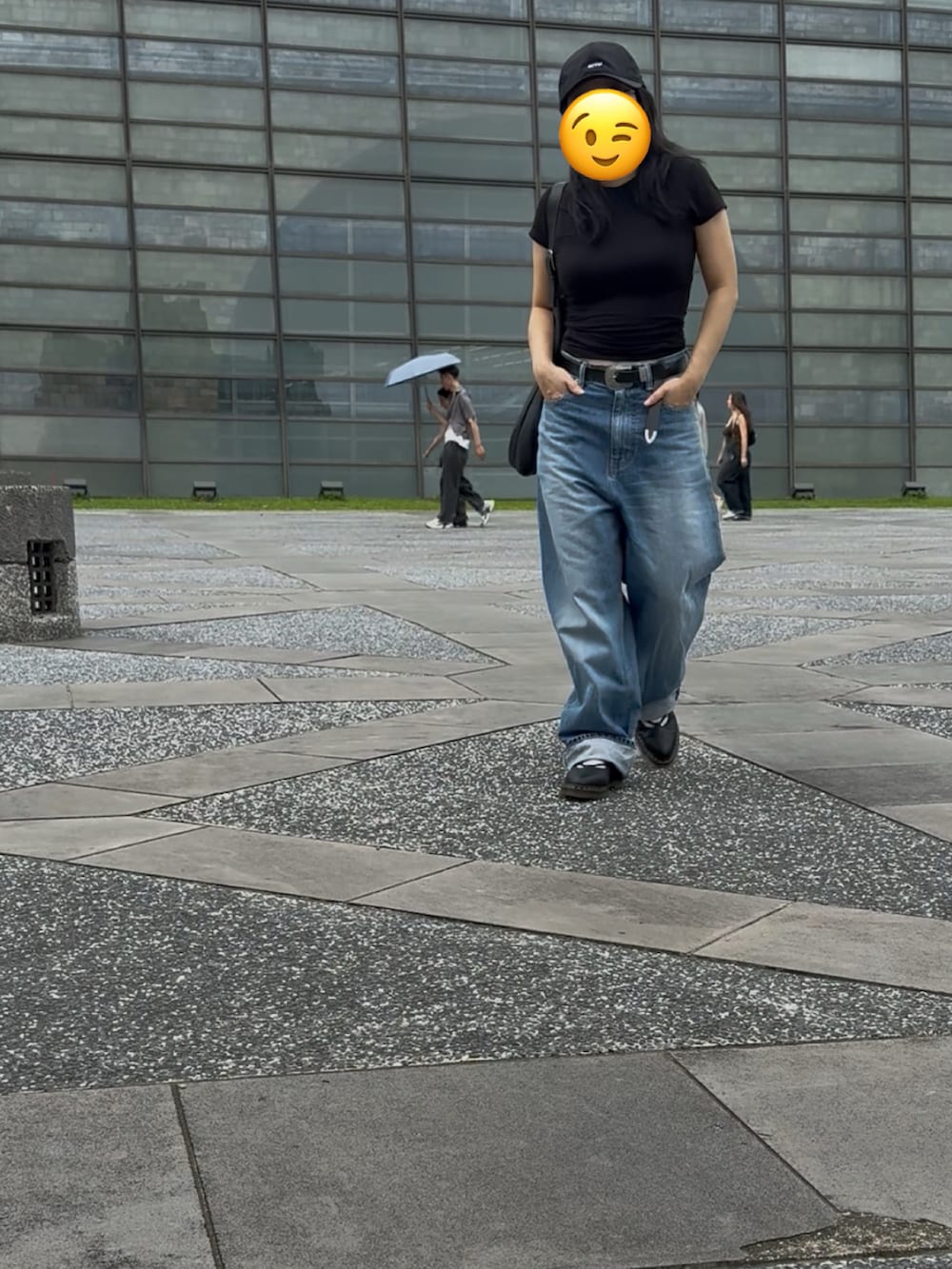 ブラック系のTシャツ/カットソー、ブラック系のドラムバッグ、ブルー系のデニムパンツを着用したレディースの秋コーディネートの5枚目の写真