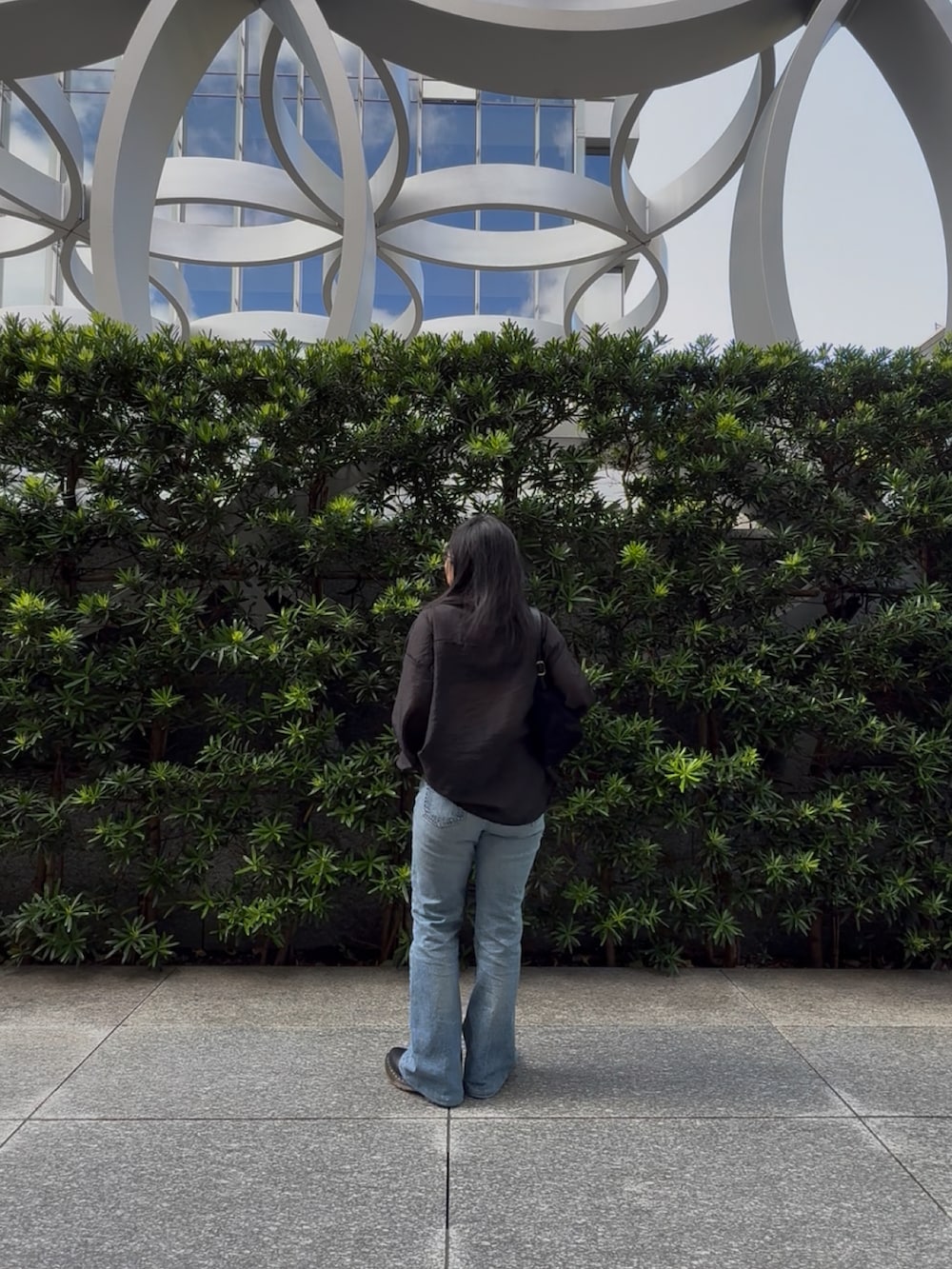 ブルー系のデニムパンツ、ブラック系のバレエシューズ、ブラック系のハンドバッグを着用したレディースの秋コーディネートの5枚目の写真