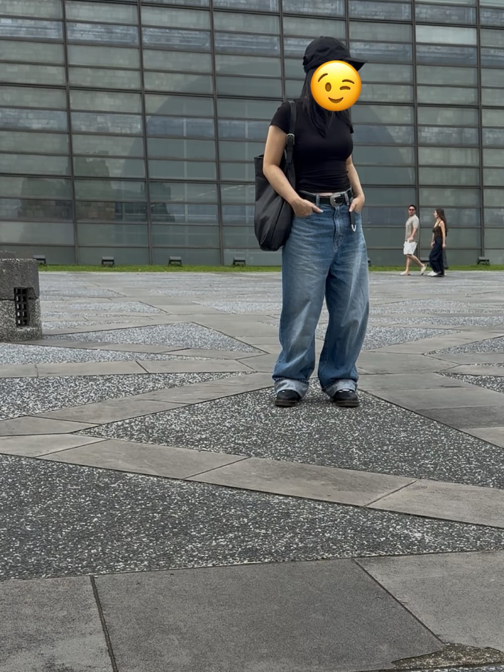 ブラック系のTシャツ/カットソー、ブラック系のドラムバッグ、ブルー系のデニムパンツを着用したレディースの秋コーディネートの4枚目の写真