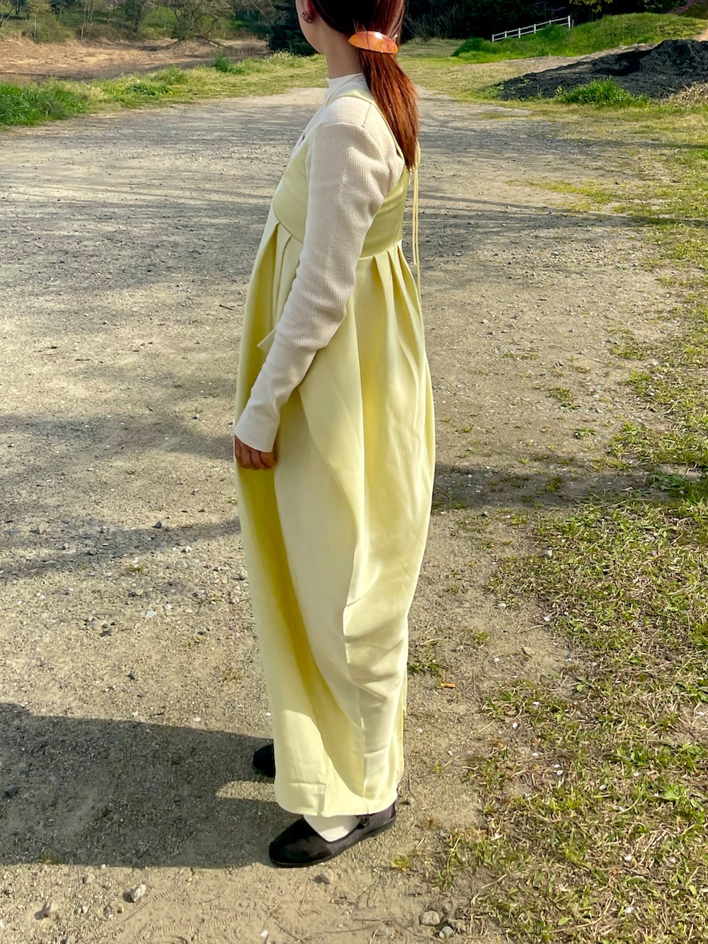 ベージュ系のハンドバッグ、イエロー系のワンピース、ブラック系のバレエシューズを着用したレディースの春コーディネートの2枚目の写真