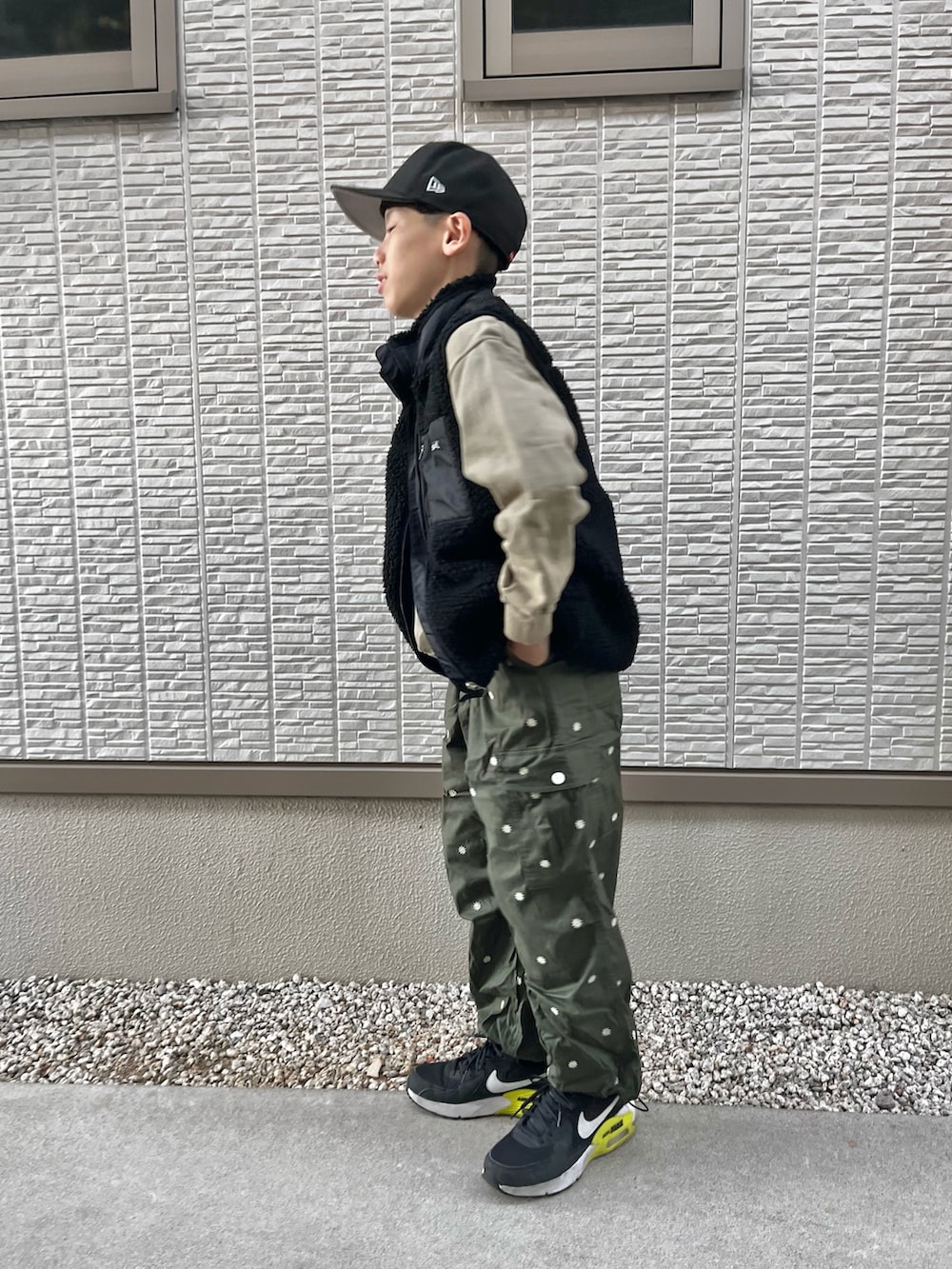 グリーン系のスウェット、ブラック系のベスト、グリーン系のカーゴパンツを着用したレディースの冬コーディネートの2枚目の写真