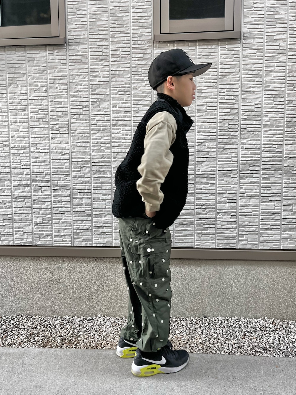 グリーン系のスウェット、ブラック系のベスト、グリーン系のカーゴパンツを着用したレディースの冬コーディネートの4枚目の写真