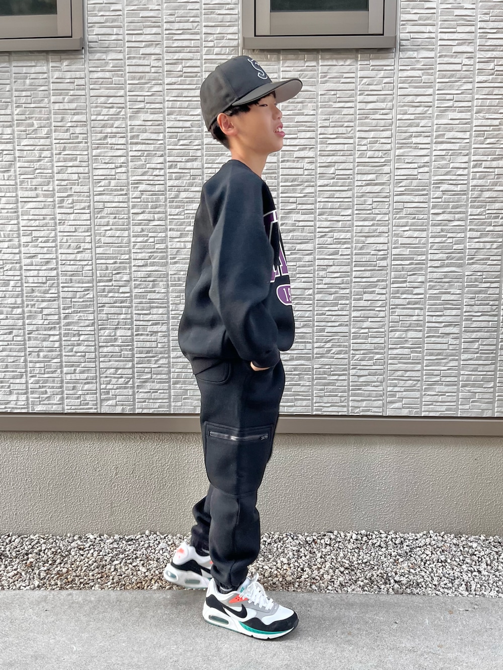 ブラック系のスウェット、ブラック系のスウェットパンツ、ホワイト系のスニーカーを着用したキッズの秋コーディネートの3枚目の写真