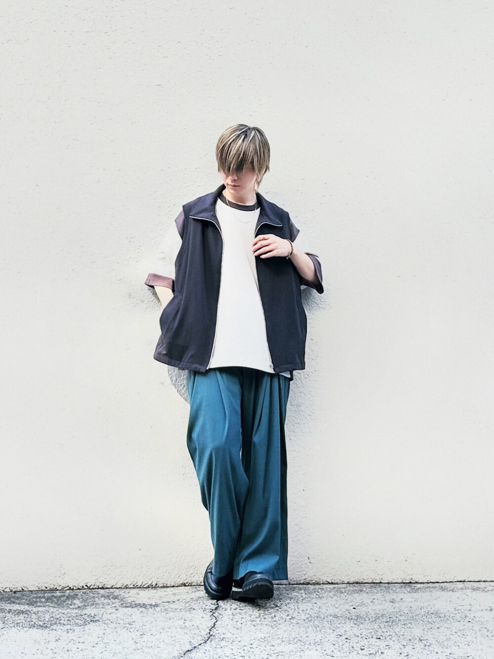 ベージュ系のTシャツ/カットソー、ブラック系のベスト、グリーン系のスラックスを着用したメンズの夏コーディネートの2枚目の写真