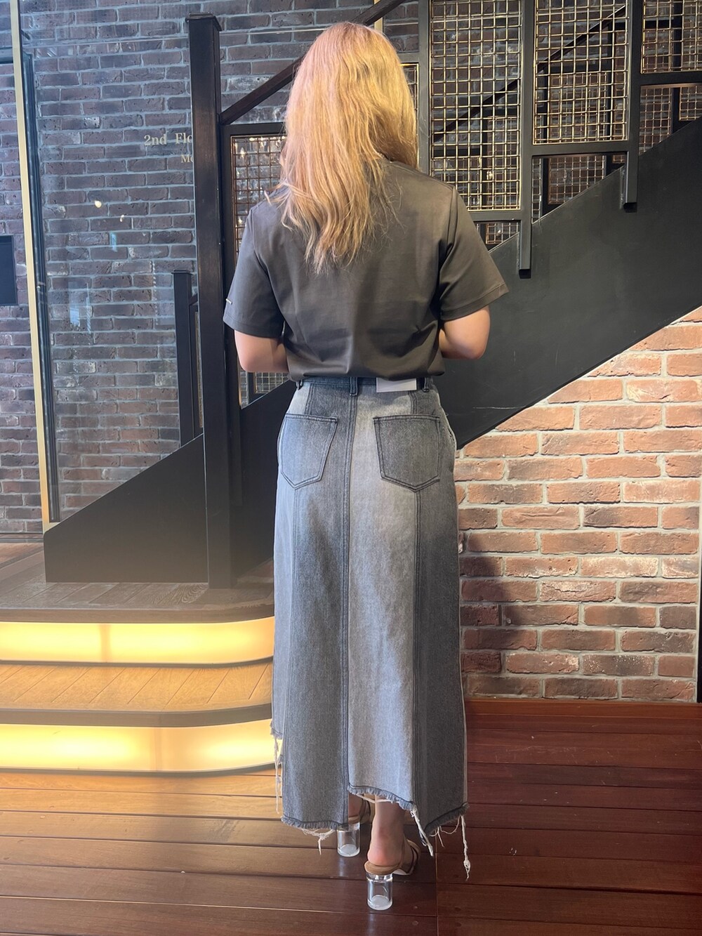 グレー系のデニムスカート、ブラック系のショルダーバッグ、グレー系のTシャツ/カットソーを着用したレディースの夏コーディネートの2枚目の写真