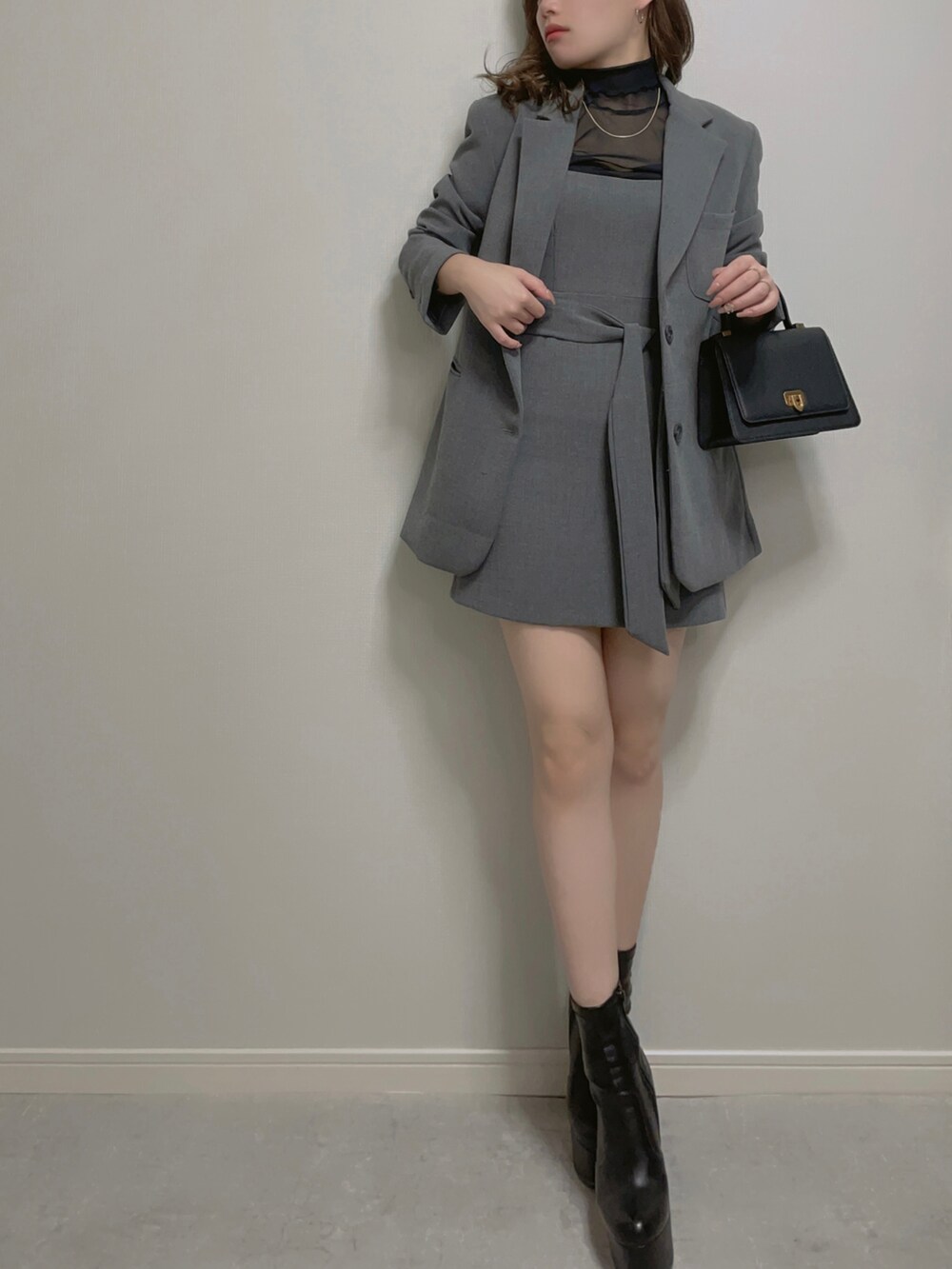 ブラック系のトップス、グレー系のセットアップ、ブラック系のブーツを着用したレディースの秋コーディネートの3枚目の写真