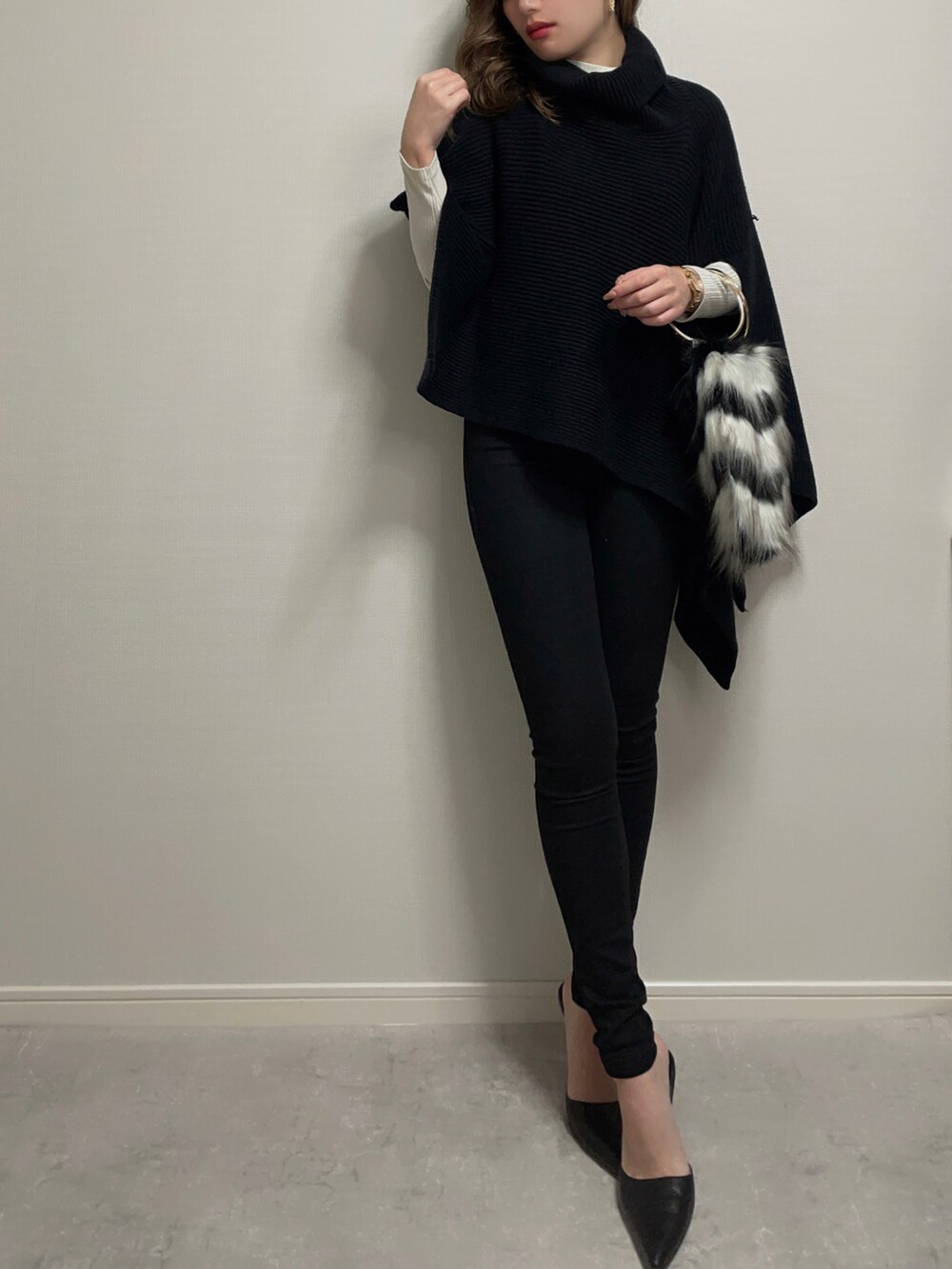 ブラック系のトップス、ホワイト系のニット/セーター、ブラック系のデニムパンツを着用したレディースの冬コーディネートの3枚目の写真