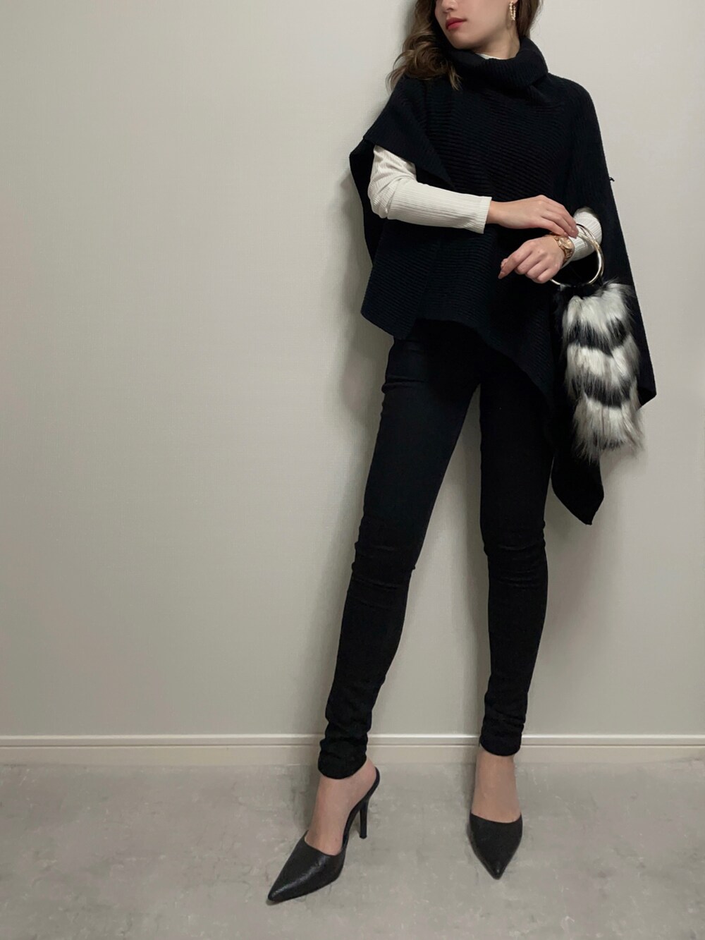 ブラック系のトップス、ホワイト系のニット/セーター、ブラック系のデニムパンツを着用したレディースの冬コーディネートの2枚目の写真