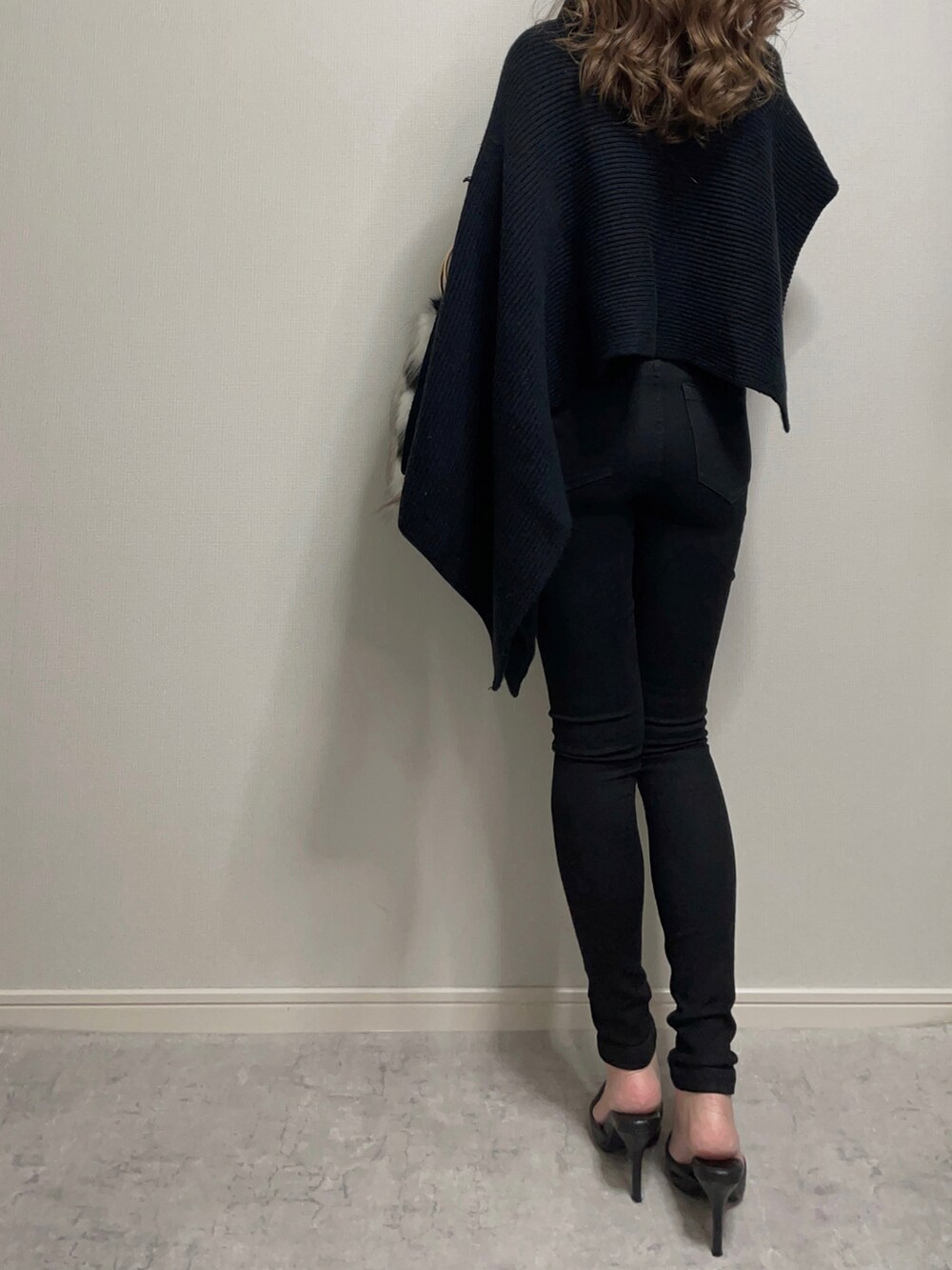 ブラック系のトップス、ホワイト系のニット/セーター、ブラック系のデニムパンツを着用したレディースの冬コーディネートの5枚目の写真