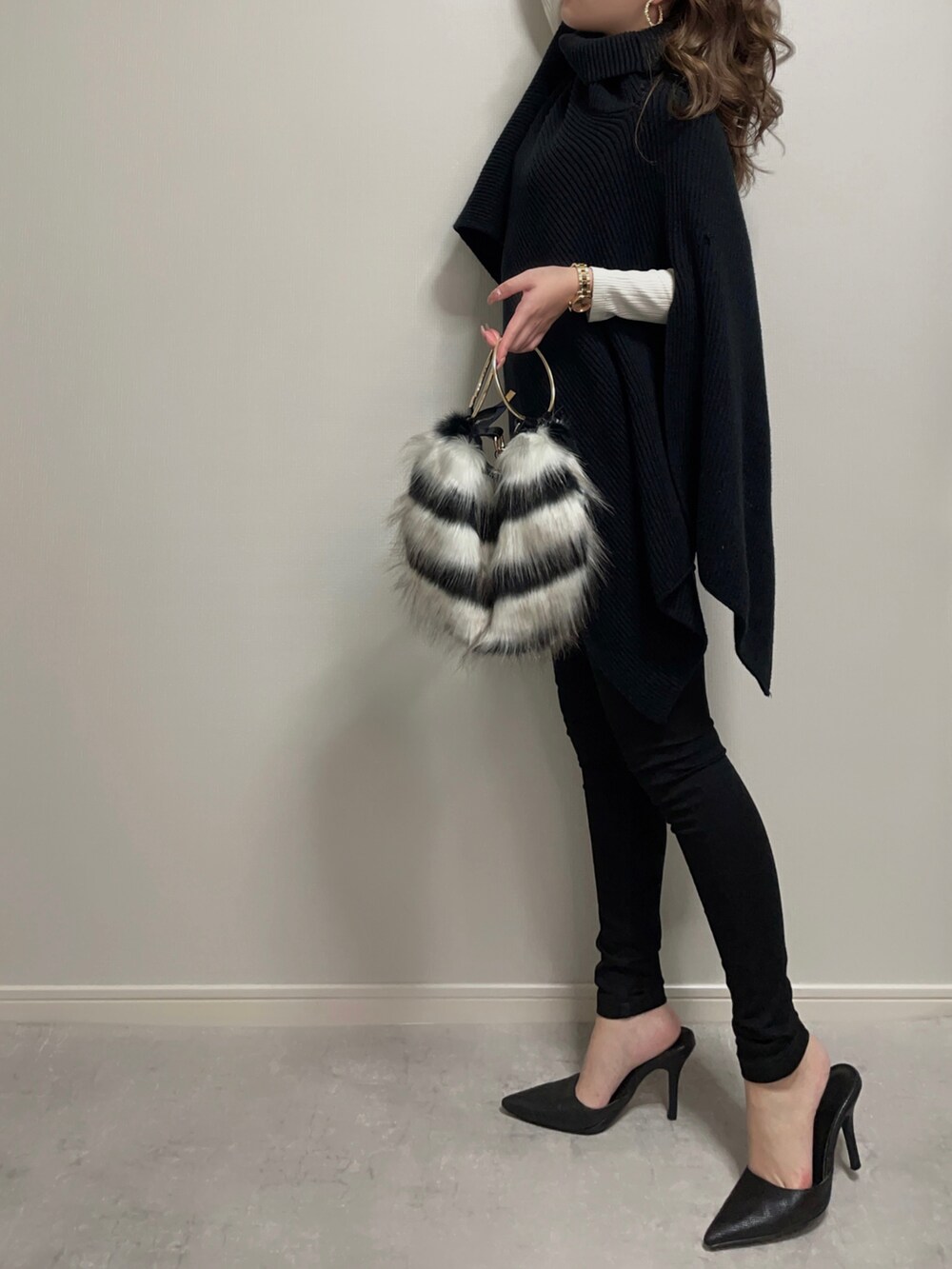 ブラック系のトップス、ホワイト系のニット/セーター、ブラック系のデニムパンツを着用したレディースの冬コーディネートの4枚目の写真